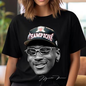 Puede incluir: Camiseta negra con una imagen en escala de grises de una persona con gafas de sol y una gorra "CHAMPIONS". La imagen incluye una firma en la parte inferior. La gorra tiene un diseño rojo y negro.