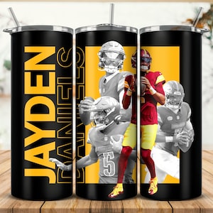May include: A black and yellow tumbler with the name "JAYDEN DANIELS" printed on it. The tumbler features a collage of football players in black and white, wearing helmets and jerseys.