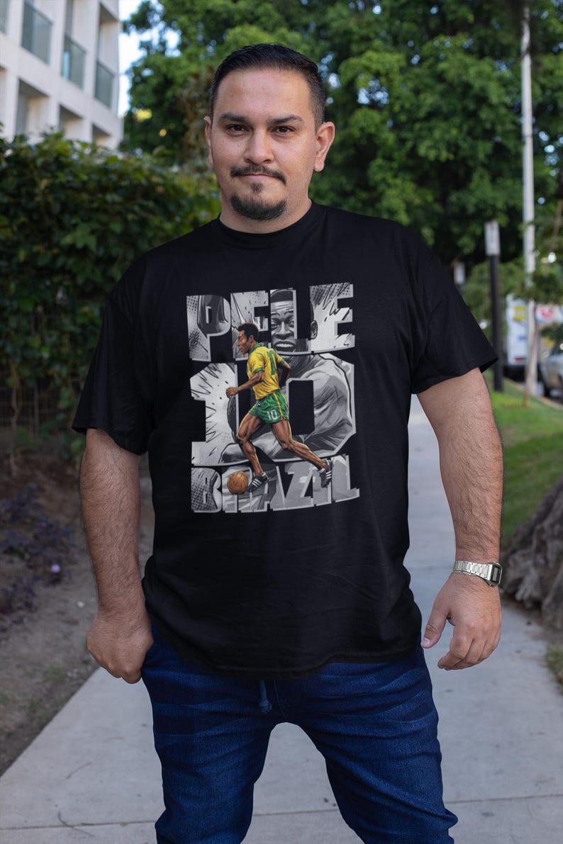 May include: Black t-shirt featuring a graphic of Pel&eacute; in a yellow and green soccer uniform, with the number 10 and the word BRAZIL. The design includes a grayscale image of Pel&eacute;'s face.