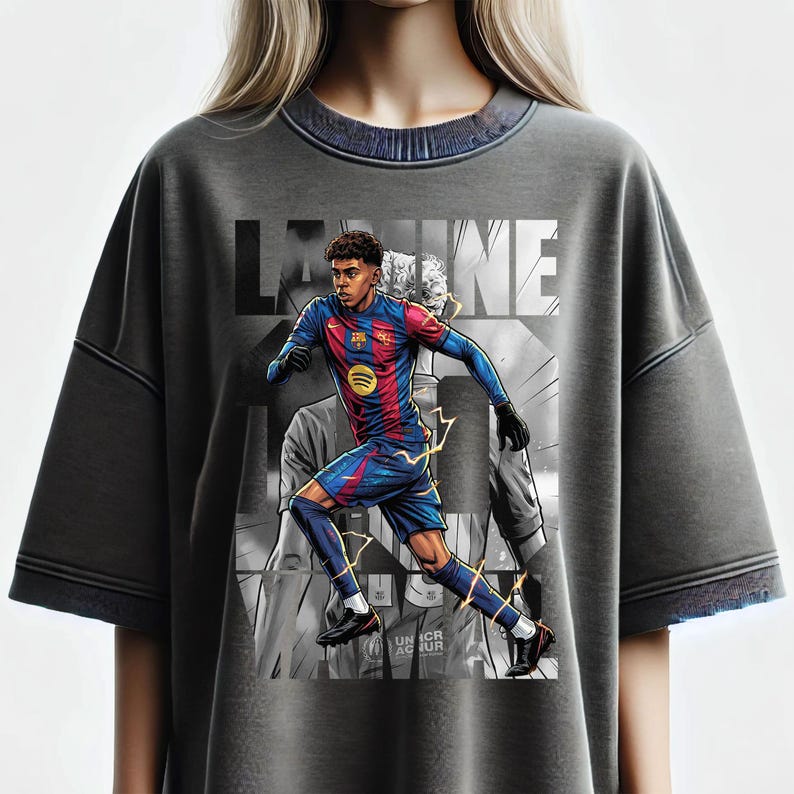 May include: Gray t-shirt featuring a graphic of a soccer player in a blue and red uniform, with lightning bolt accents. The shirt has the word "LAINE" in large letters across the top. The player is running, with a blurred background.