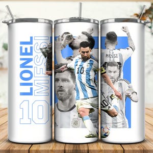 Puede incluir: Un vaso de acero inoxidable blanco con un diseño azul y blanco con Lionel Messi, un famoso jugador de fútbol. El vaso tiene el texto "Lionel Messi 10" impreso en el lateral.