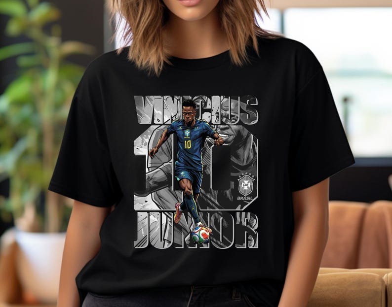 May include: Black t-shirt featuring a graphic of a soccer player in a blue uniform, with the name "VINICIUS JR" and the number "10" in white. The Brazilian flag and team logo are also visible.