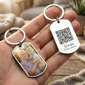 Könnte beinhalten: Zwei silberne Schlüsselanhänger. Ein Schlüsselanhänger zeigt ein Foto eines Mannes und eines Kindes. Der andere Schlüsselanhänger hat einen QR-Code und das Wort "Grandpa" mit einem Datum. Beide Schlüsselanhänger haben einen silbernen Ring.
