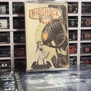 May include: A BioShock Infinite cassette tape with a cream-colored cover featuring a woman in a white dress standing before a large mechanical figure. The title BioShock Infinite is printed in a stylized font at the top of the cassette case.