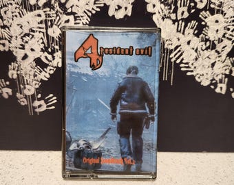May include: A cassette tape with a blue and white image of a man in a jacket walking through a snowy forest. The text "Resident Evil 4" is printed in red on the cassette tape. The text "Original Soundtrack Vol. 2" is printed in orange on the cassette tape.