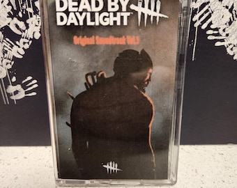 May include: A cassette tape with a black and white image of a person wearing a black hooded jacket. The text on the cassette tape reads "Dead by Daylight Original Soundtrack Vol. 1".
