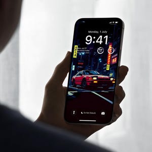 Könnte beinhalten: Ein Smartphone zeigt ein dynamisches Hintergrundbild mit einem roten Sportwagen auf einer neonbeleuchteten Straße bei Nacht. Der Bildschirm zeigt das Datum, Montag, 1. Juli, und die Uhrzeit 9:41 Uhr. Das Telefon wird in einer Hand gehalten.