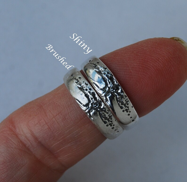 K&ouml;nnte beinhalten: Zwei silberne Ringe mit einem strukturierten Design. Ein Ring hat eine gl&auml;nzende Oberfl&auml;che, w&auml;hrend der andere eine geb&uuml;rstete Oberfl&auml;che hat. Die Ringe sind mit "Shiny" und "Brushed" beschriftet.