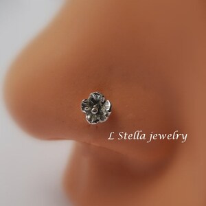 May include: A silver flower nose ring with a small clear gem in the center.