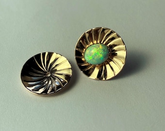 May include: A pair of gold-colored stud earrings. One earring features a vibrant green opal gemstone set in a sunburst design. The other earring is a matching gold-colored disc with a spiral pattern.