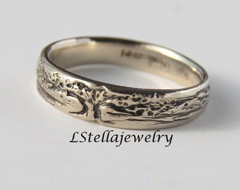 May include: A silver band ring with a detailed tree design. The ring is engraved with the text "14K" on the inside.