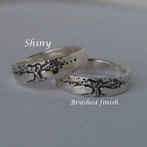K&ouml;nnte beinhalten: Zwei silberne Ringe mit einem Baumdesign. Ein Ring hat eine gl&auml;nzende Oberfl&auml;che, w&auml;hrend der andere eine geb&uuml;rstete Oberfl&auml;che hat. Der Text "Shiny" befindet sich &uuml;ber dem gl&auml;nzenden Ring, und der Text "Brushed finish" befindet sich unter dem geb&uuml;rsteten Ring.