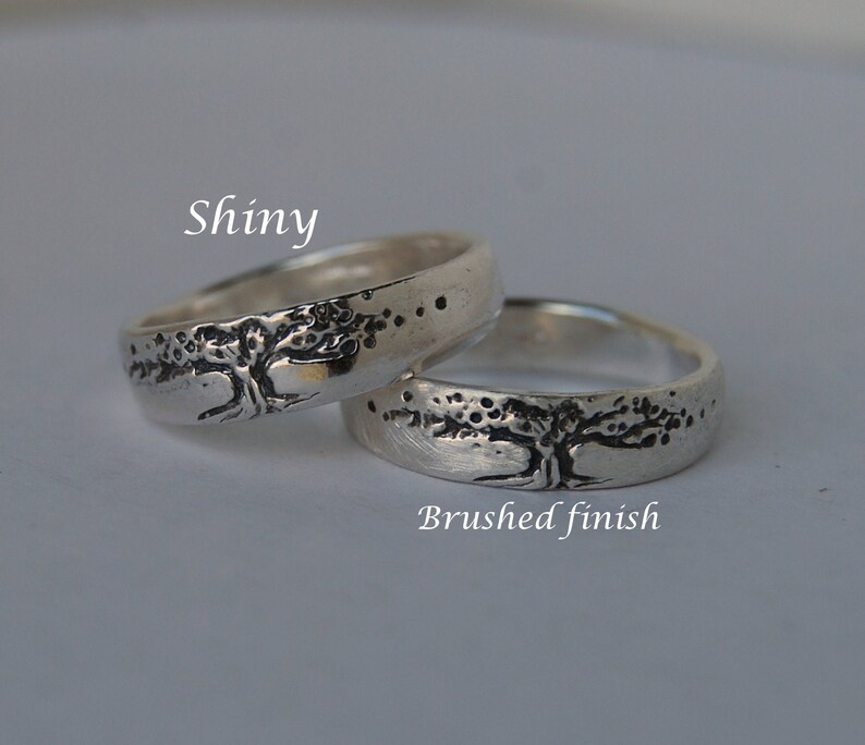 K&ouml;nnte beinhalten: Zwei silberne Ringe mit einem Baumdesign. Ein Ring hat eine gl&auml;nzende Oberfl&auml;che, w&auml;hrend der andere eine geb&uuml;rstete Oberfl&auml;che hat. Der Text "Shiny" befindet sich &uuml;ber dem gl&auml;nzenden Ring, und der Text "Brushed finish" befindet sich unter dem geb&uuml;rsteten Ring.