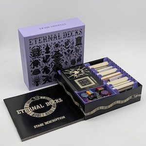 以下が含まれることがあります： Eternal Decksというタイトルのボードゲームセット。黒いイラストが描かれた薄紫色の箱、カードの束と小さな色付きトークンを収納する紫色の仕切りがある黒いゲームボックス、金色の文字が書かれた黒いマニュアルが含まれています。