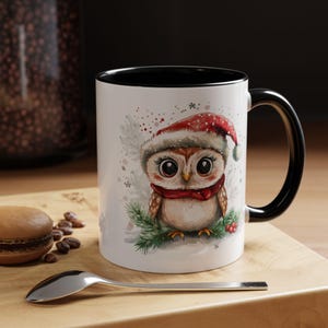 Puede incluir: Taza de cerámica blanca con interior y asa negros. La taza presenta una ilustración de acuarela de un lindo búho con un gorro de Papá Noel y una bufanda roja. El búho está posado en una ramita de pino.