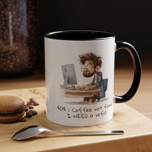 May include: White ceramic coffee mug with a black interior and handle. The mug features a cartoon illustration of a person working on a computer with the text "404: Coffee not found I NEED a refill!"