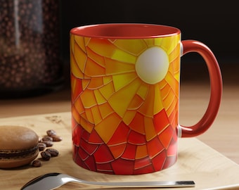 Könnte beinhalten: Eine rote Keramiktasse mit einem Buntglasdesign einer Sonne, die über einer roten und orangefarbenen Landschaft untergeht. Die Tasse hat einen weißen Henkel.
