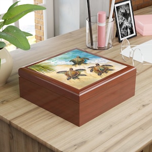 May include: A wooden box with a hinged lid. The lid features a colorful illustration of three sea turtles swimming on a sandy beach with ocean waves in the background.