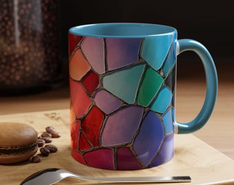 Pode incluir: Uma caneca de cerâmica azul com um design de mosaico colorido. O padrão de mosaico apresenta tons de vermelho, laranja, amarelo, verde, azul, roxo e rosa.