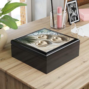 May include: Black wooden box with a hinged lid. The lid features a colorful abstract design with three gold hearts.