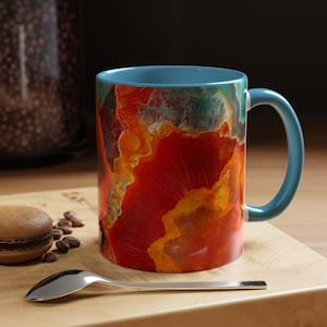 Könnte beinhalten: Eine blaue Keramiktasse mit einem bunten Achatmuster. Das Muster zeigt Farbtöne von Rot, Orange, Gelb und Grün.