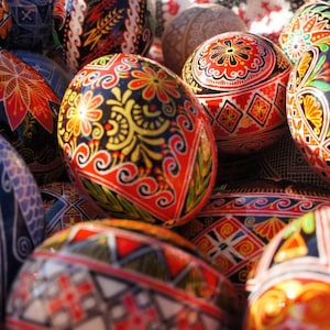 May include: A collection of intricately decorated Easter eggs, each with a unique pattern of colourful designs. The eggs are painted in a variety of colours, including red, blue, green, yellow, and black. The designs are intricate and detailed, and they are all different.