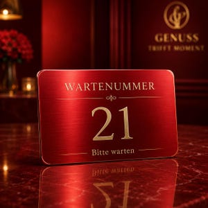 Könnte beinhalten: Ein rechteckiges, rotes Metallschild mit abgerundeten Ecken, das den goldenen Schriftzug WARTENUMMER, die Zahl 21 und den Text Bitte warten trägt. Die Oberfläche hat eine gebürstete Metallstruktur und reflektiert Licht, was ein formelles Design ergibt.