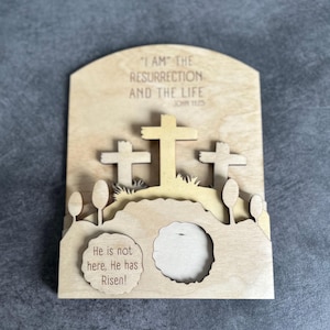 May include: Wooden Easter card with a 3D design of three crosses and a tomb with the text "I AM THE RESURRECTION AND THE LIFE JOHN 11:25" and "He is not here, He has Risen!"