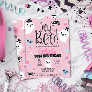 May include: A rectangular pink Halloween-themed invitation card featuring white ghosts wearing black top hats, black spiders, blue skulls, and sweets. The text reads Hey Boo! You're invited to a Halloween-themed party for Evelyn's 9th birthday.