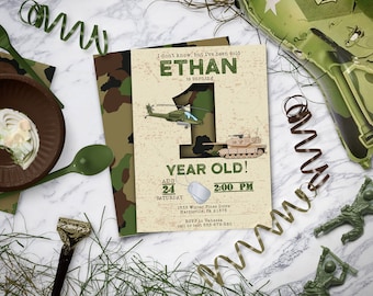 May include: A military-themed birthday party invitation with the text "Ethan is turning 1 year old!" and the date and time. The invitation features a helicopter and a tank illustration, with camouflage patterns and green accents. Includes a green fork, spoon, and a plate with food.