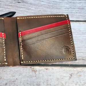 Cartera clásica de piel de plena flor con nueve bolsillos, diseño unisex elegante y detalles de colores vibrantes.