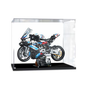 Könnte beinhalten: Ein weißes, blaues und rotes LEGO® BMW® Motorradmodell in einer transparenten Vitrine mit schwarzem Sockel. Das Motorrad hat ein detailliertes Design mit einer Windschutzscheibe, Rädern und einem Sitz. Die Vitrine hat einen schwarzen Sockel und eine transparente Acrylglasabdeckung.