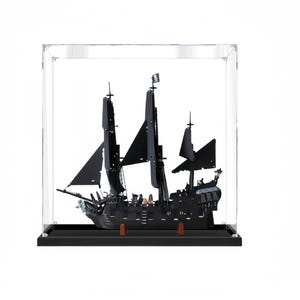 May include: A black model ship with tall masts and black sails, displayed inside a clear acrylic case. The ship has intricate details and a pirate flag. The base is black, and the case is square.