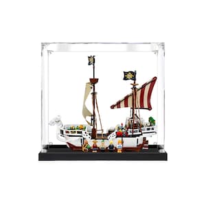 May include: A model pirate ship in a clear display case. The ship is white and brown with red and white striped sails and black flags. Includes miniature figures. The case has a black base.