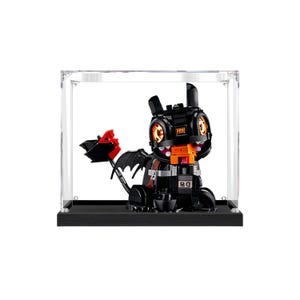 May include: A black dragon figure made of interlocking blocks, with orange and red accents, displayed inside a clear acrylic case on a black base. The dragon has large eyes and wings, and is a collectible item.