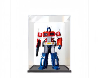 Puede incluir: Un juguete robot rojo y azul, Optimus Prime, se muestra en una vitrina de acrílico transparente con una base negra. El robot está en su modo robot, con los brazos y las piernas extendidos.