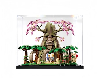 May include: A Lego set of a large tree with pink flowers, a stone face, and small figures standing in front of it. The set is displayed in a clear acrylic display case.