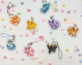 May include: A selection of colourful acrylic charms featuring cartoon characters. Each charm has a unique design and is attached to a string or strap. The charms are surrounded by star-shaped and round beads in various colours.