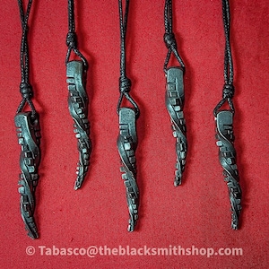 May include: Five black metal pendants with a twisted, geometric design, hanging from black cords on a red background.  The pendants are all the same shape and size, and they have a unique, modern look.