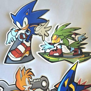 Op de afbeelding: Een verzameling kleurrijke, gestanste stickers met personages uit de Sonic the Hedgehog-videogameserie. De stickers bevatten Sonic, Tails, Shadow, Amy Rose en Dr. Eggman. Op het schort van Dr. Eggman staat "#1 Chef in the World."