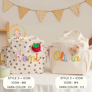 May include: Two beige corduroy tote bags with embroidered names and icons. One bag has a strawberry icon and the name "Remi" in colorful yarn. The other bag features a teddy bear icon and the name "Olivia". Both bags have side pockets.