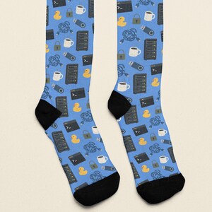 May include: A pair of light blue crew socks featuring a repeating pattern of yellow rubber ducks, black server racks, white coffee mugs, gray padlocks, blue USB drives, tangled blue cables, and black computer terminal windows with white text.