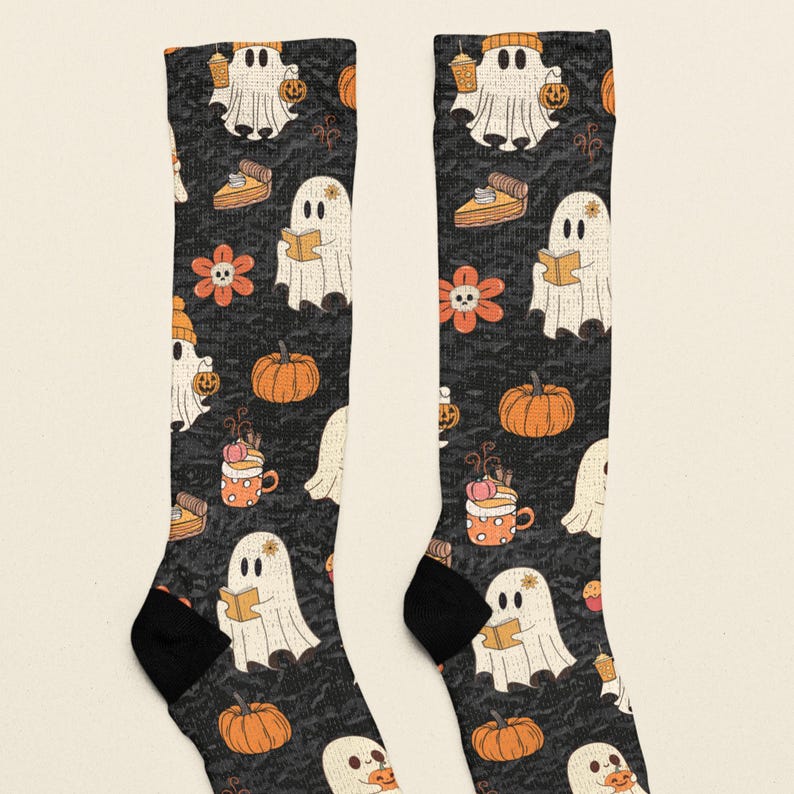 Puede incluir: Un par de calcetines negros con un patr&oacute;n repetitivo de fantasmas blancos, calabazas naranjas, porciones de pastel de calabaza, tazas naranjas con crema batida y flores naranjas con centros en forma de calavera.