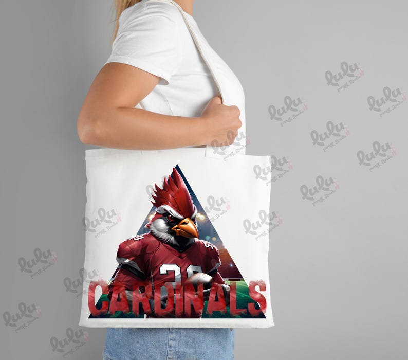 Pu&ograve; includere: Borsa tote bianca con una mascotte di cardinale rosso che indossa una maglia da football con la scritta "CARDINALS" stampata sulla borsa.