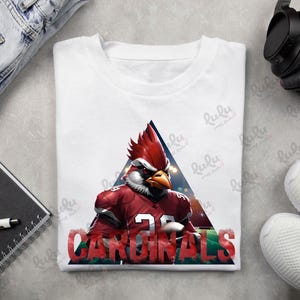 Pu&ograve; includere: Maglietta bianca con un cardinale rosso che indossa una divisa da football e la parola "CARDINALS" in lettere rosse.