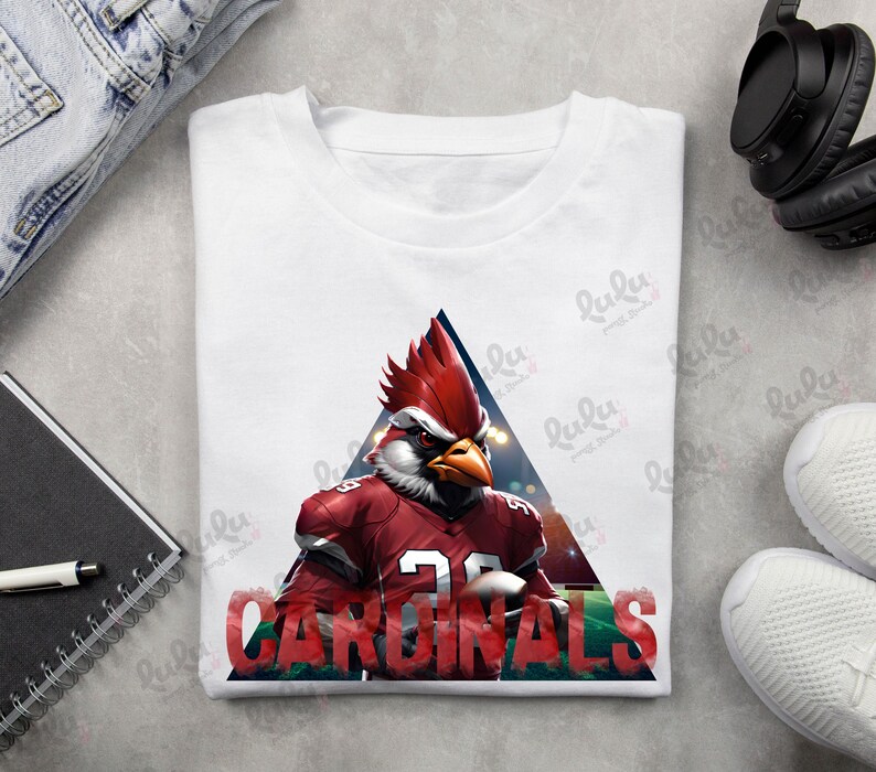 Pu&ograve; includere: Maglietta bianca con un cardinale rosso che indossa una divisa da football e la parola "CARDINALS" in lettere rosse.