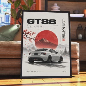 May include: A framed poster featuring a white Toyota GT86 sports car from the rear view. The design includes a large red sun, Mount Fuji, cherry blossoms, and a pagoda. Text reads GT86, Toyota GT86, 2.0L Boxer-Four, Rear-Wheel Drive, 2012-2021, and Japanese text.
