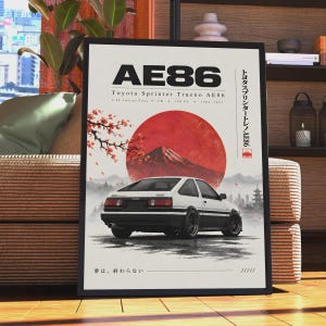 May include: A framed poster featuring a white and black Toyota Sprinter Trueno AE86 car, a large red sun, and Mount Fuji. The text includes AE86, Toyota Sprinter Trueno AE86, 1.6L Inline-Four, FR, 130 PS, 1983-1987, Japanese characters, and 夢は、終わらない.