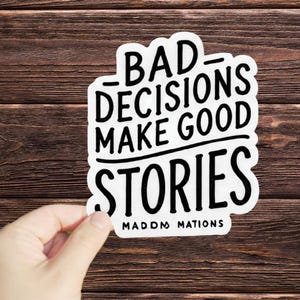 May include: White sticker with black text that reads "Bad decisions make good stories" with the words "MadDM Nations" at the bottom.