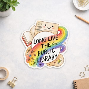 May include: A colorful sticker with the text "LONG LIVE THE PUBLIC LIBRARY." The design includes a rainbow, an open book, a library card, and various small illustrations. The sticker has a white border and is on a white surface.